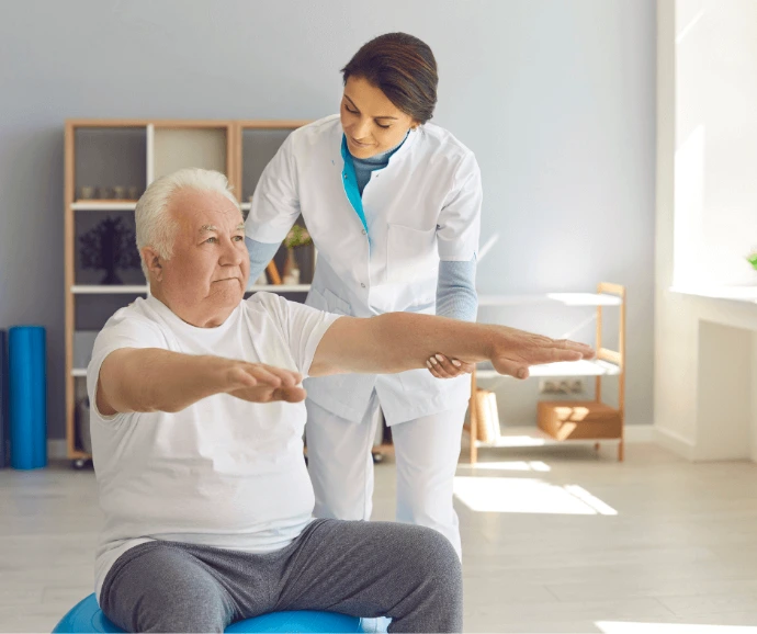 Kinésithérapeute aidant un patient âgé lors d’exercices d’équilibre à domicile